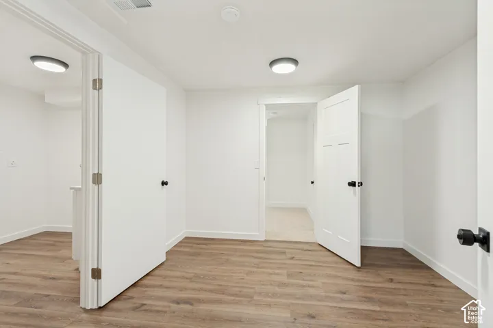 Interior space featuring wood-finish flooring, white panel doors with matte black hardware, and flush-mount ceiling lighting