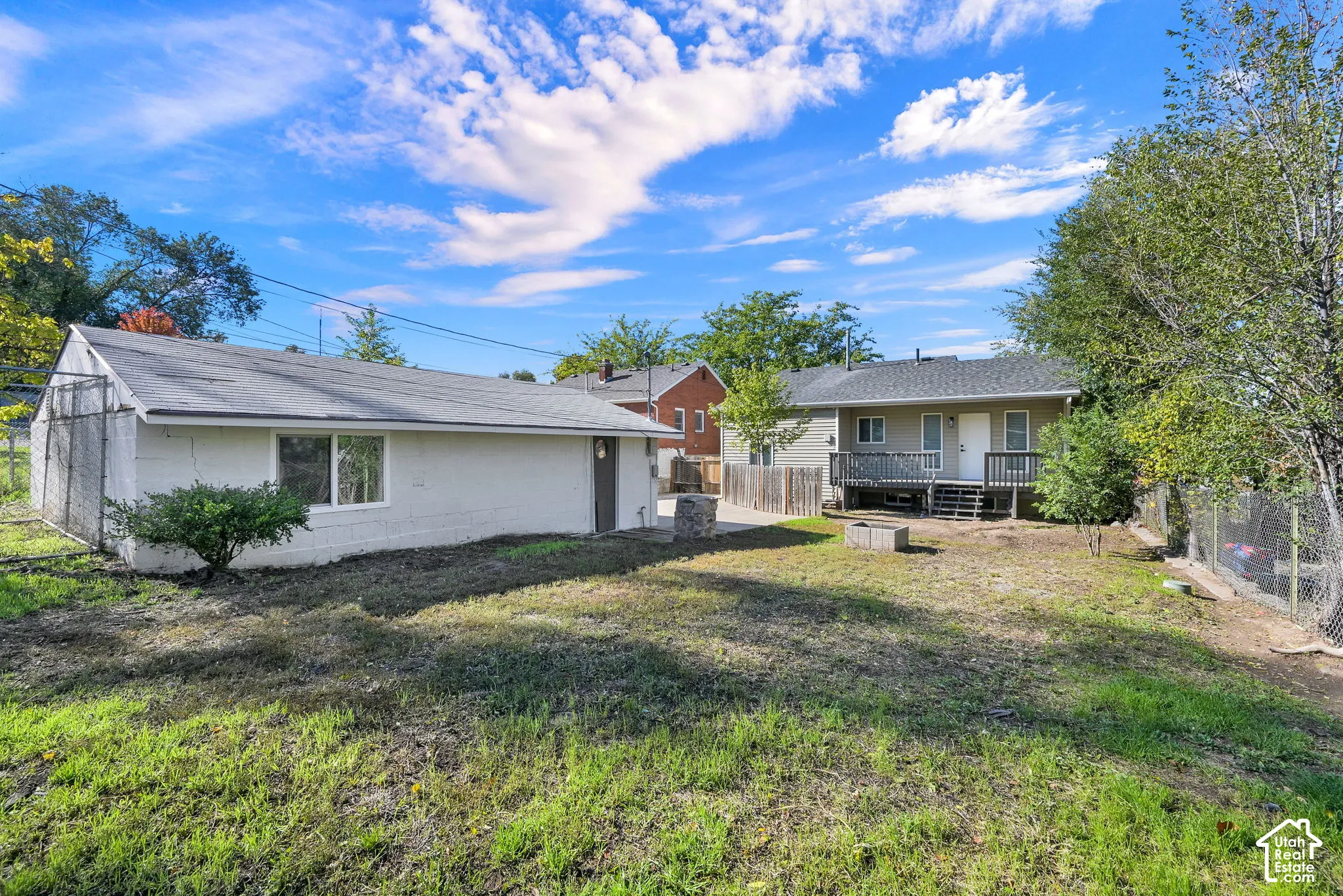 Exterior features include a detached garage with a white masonry finish, an elevated wood deck, and a fenced yard with mature trees