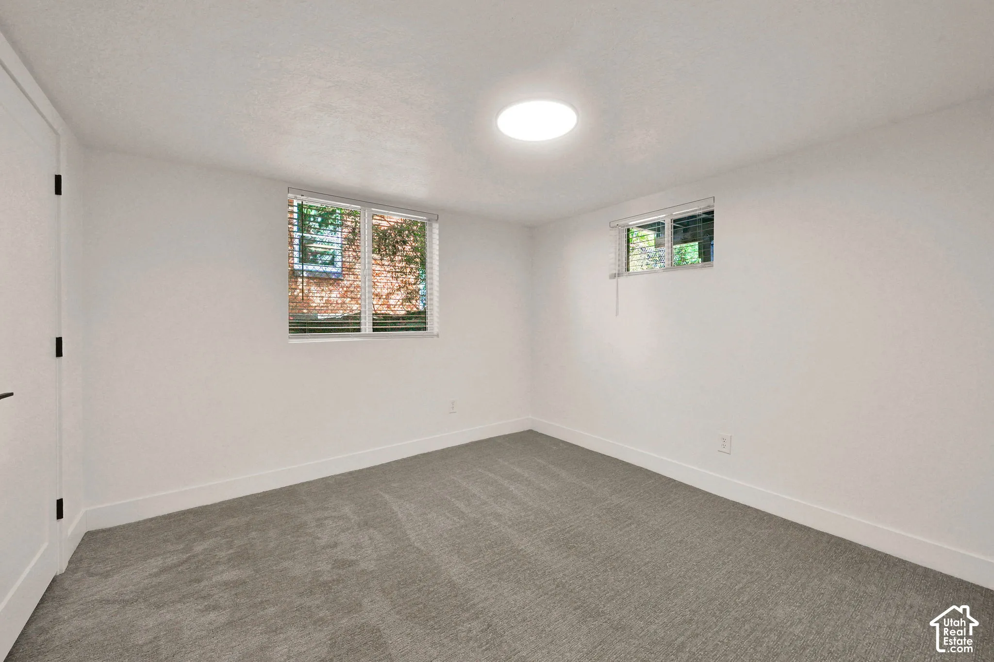 Neutral interior space featuring wall-to-wall carpeting, recessed ceiling lighting, and dual windows with horizontal blinds