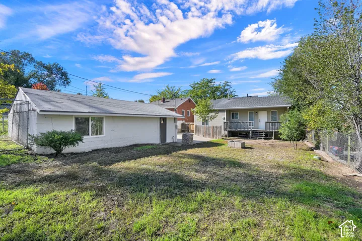 Exterior features include a detached garage with a white masonry finish, an elevated wood deck, and a fenced yard with mature trees