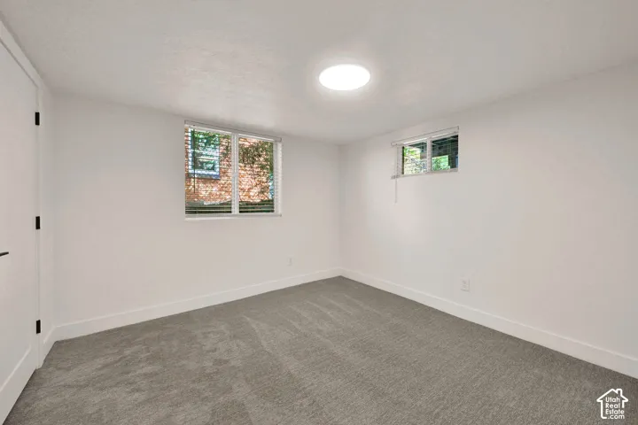 Neutral interior space featuring wall-to-wall carpeting, recessed ceiling lighting, and dual windows with horizontal blinds