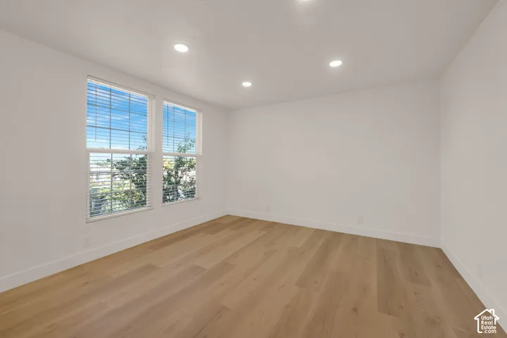 Neutral interior space featuring wood-finish flooring, recessed lighting, and dual windows