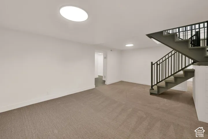 Open interior space featuring wall-to-wall carpeting, recessed ceiling lighting, and a staircase with metal railings