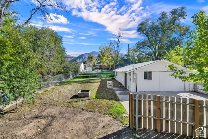 Backyard featuring a concrete driveway, detached garage, stone-accented perimeter, and mountain backdrop