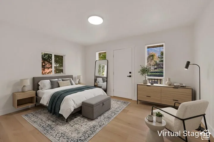 Bright room featuring wood-finish flooring, white walls, flush-mount ceiling lighting, and multiple windows