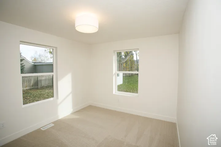 Interior space featuring neutral wall tones, carpeted flooring, two windows, and a drum-style ceiling light fixture