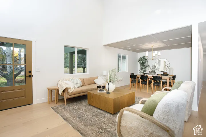 Vaulted ceilings, wood-finish flooring, multi-pane entry door, recessed ceiling grid in the dining area, and a multi-arm hanging light fixture