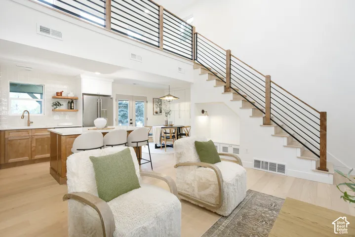 Open-concept interior featuring wood-finish flooring, a kitchen island with stone countertops, a staircase with custom wood-and-metal railings, and built-in under-stair cabinetry