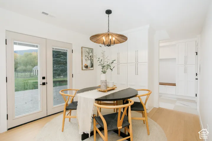 Custom floor-to-ceiling white cabinetry, wood-finish flooring, glass-paneled double doors, woven textured pendant lighting, and built-in mudroom storage with a wooden bench