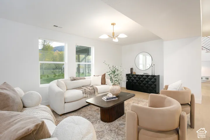 Living area featuring dual-pane windows, light-toned wood-finish flooring, and a multi-arm metallic chandelier