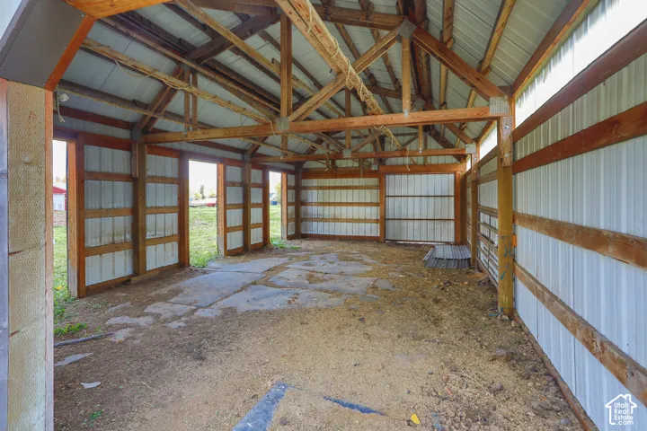 Open-bay outbuilding featuring exposed wood timber framing, corrugated metal wall panels, a metal roof, and concrete flooring
