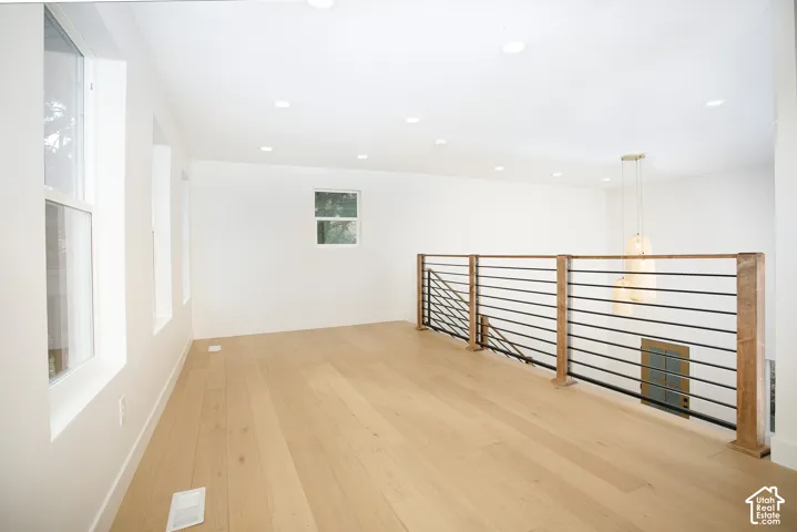 Open loft area featuring wood-finish flooring, recessed lighting, and a custom railing with wood posts and horizontal metal balusters