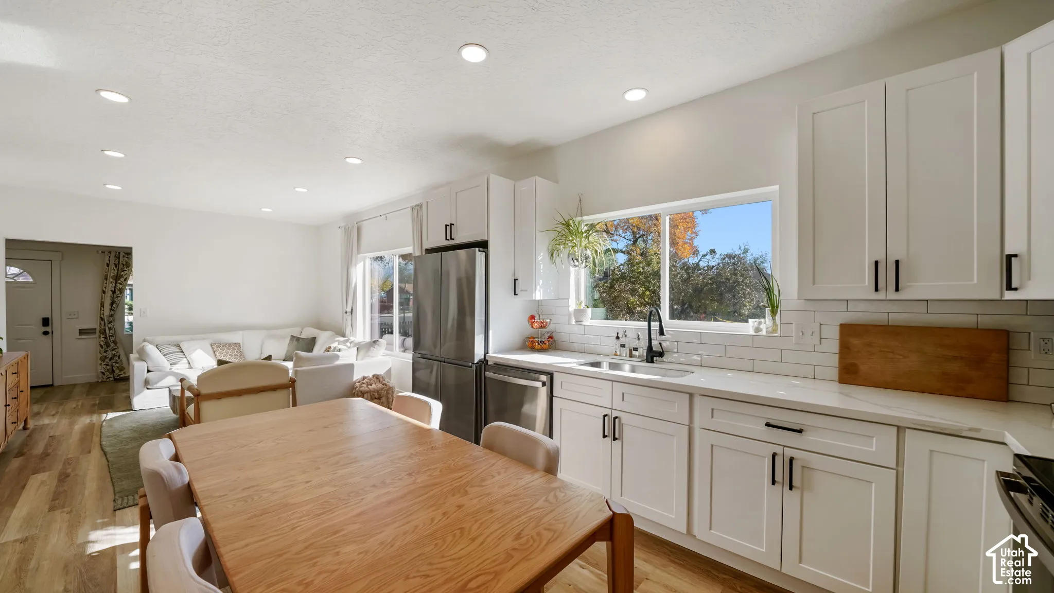 Kitchen featuring white shaker-style cabinetry, stainless steel appliances, white subway tile backsplash, quartz countertops, and recessed lighting
