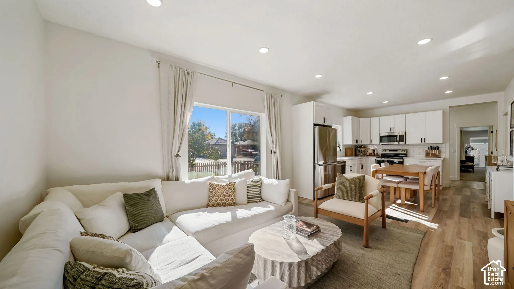 Open-concept interior featuring wood-finish flooring, recessed lighting, and kitchen cabinetry with a glossy finish and stainless steel appliances