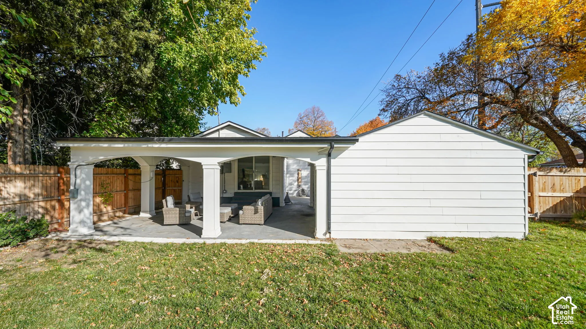 Covered patio featuring architectural columns, stone-tile flooring, and white horizontal siding