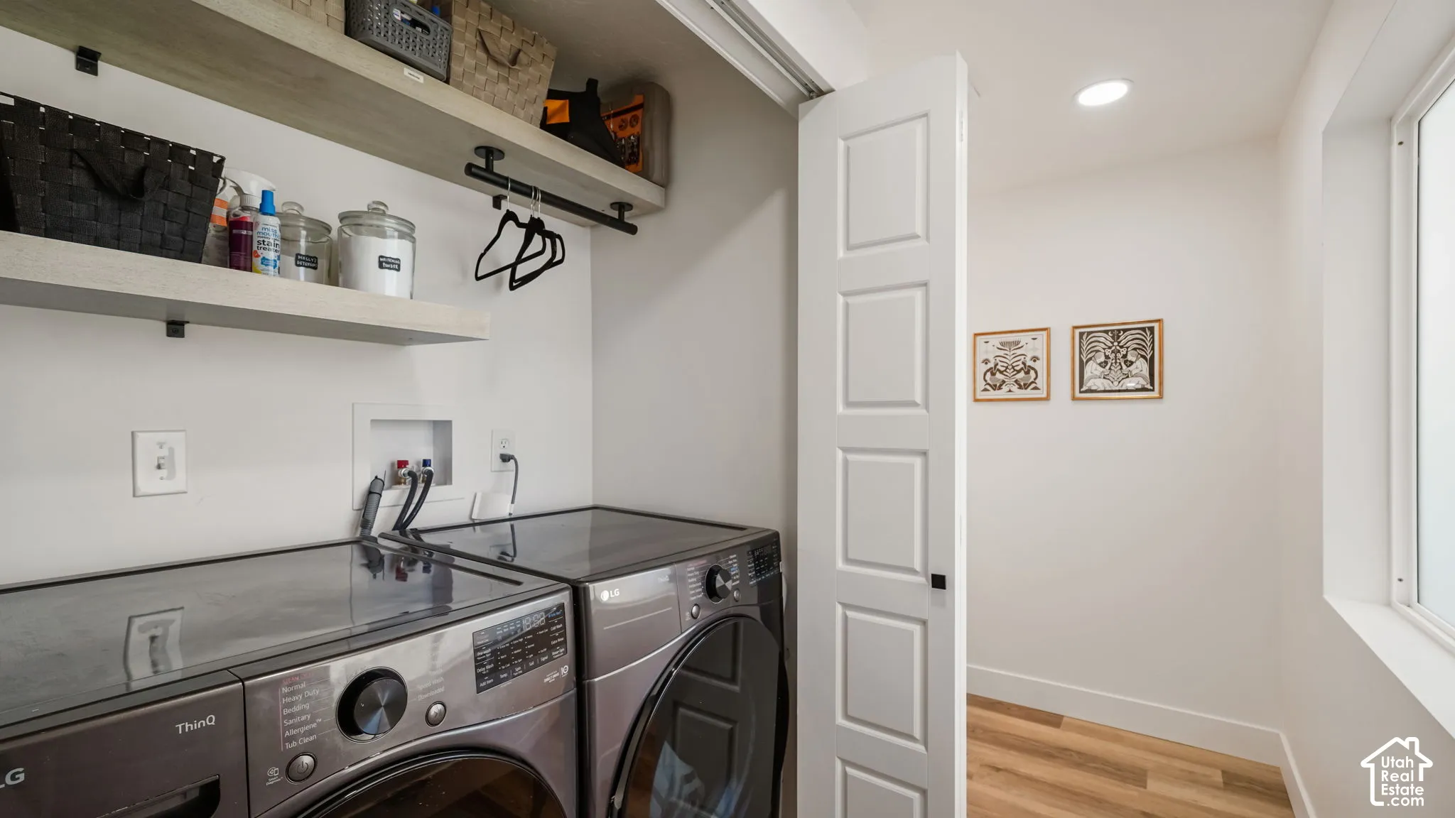 Laundry space featuring wood-finish flooring, two-tier floating shelving with integrated matte black hardware, and recessed ceiling lighting