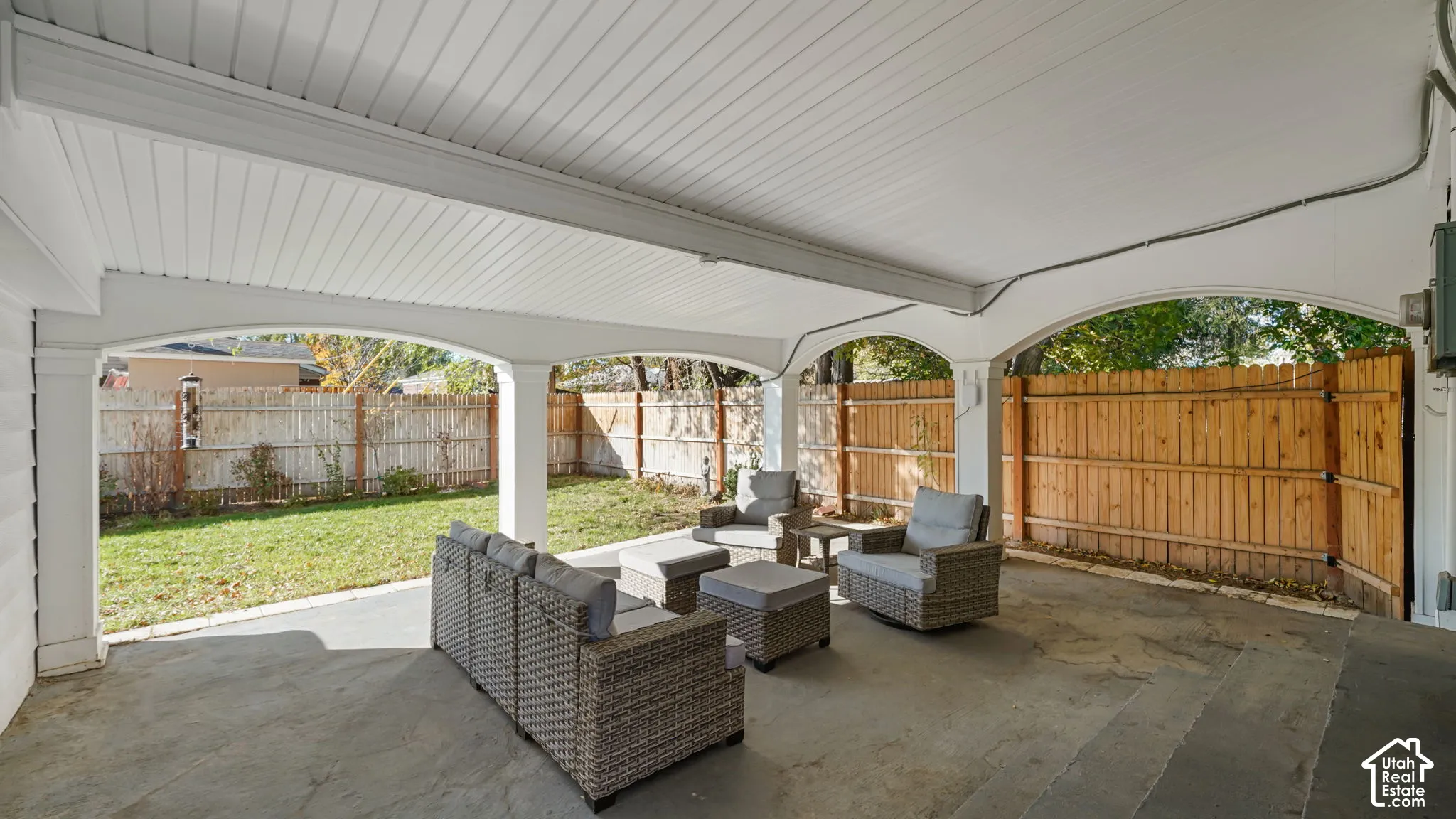 Covered patio featuring architectural arched supports, a tongue-and-groove ceiling, concrete flooring, and a fully fenced backyard