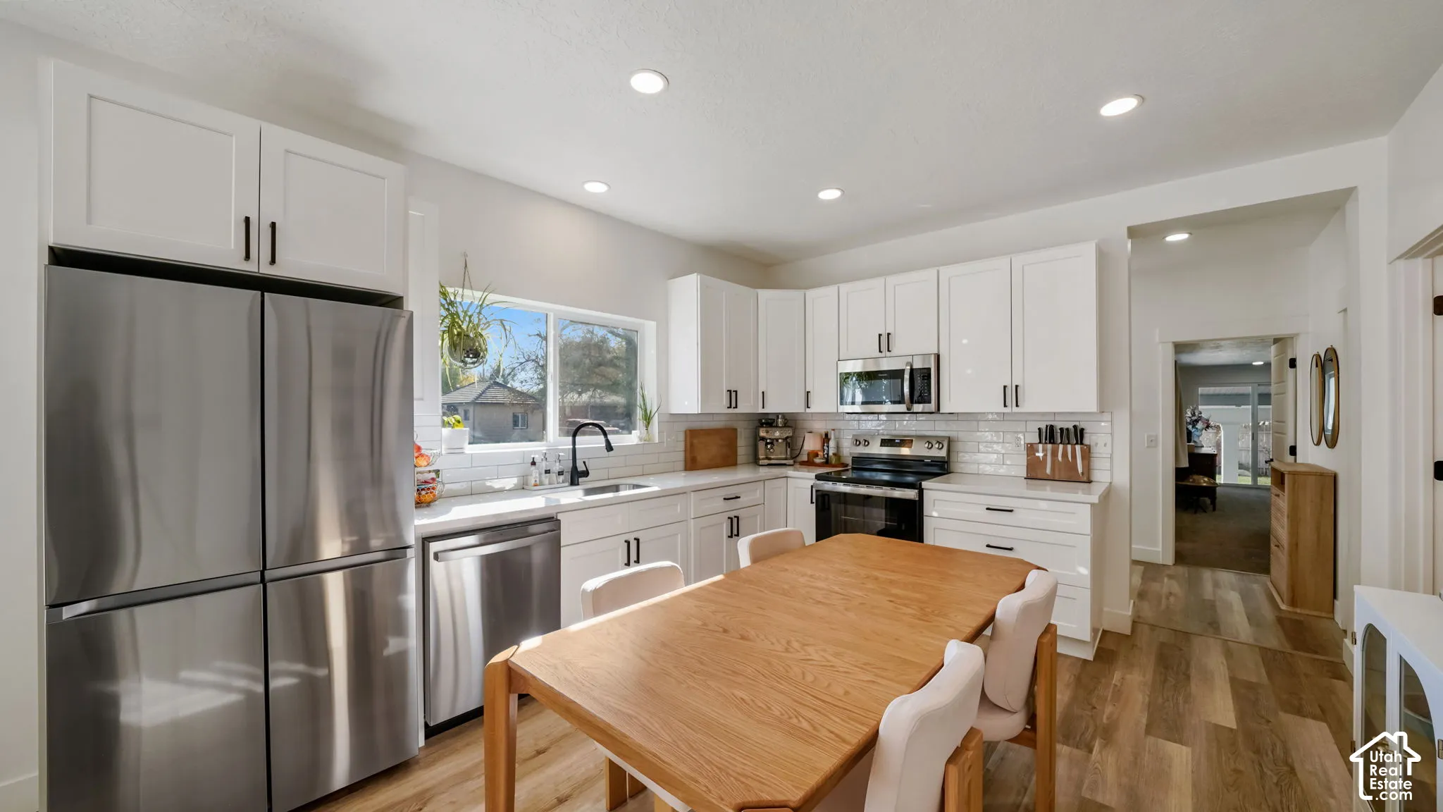 Kitchen featuring white shaker-style cabinetry, stainless steel appliances, white subway tile backsplash, recessed lighting, and wood-finish flooring