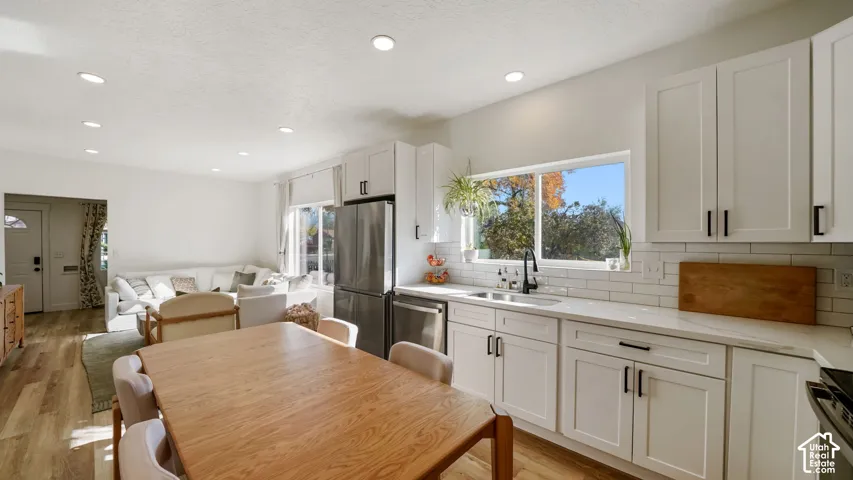 Kitchen featuring white shaker-style cabinetry, stainless steel appliances, white subway tile backsplash, quartz countertops, and recessed lighting