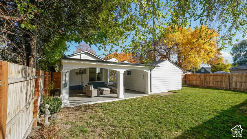 Covered patio with arched architectural supports, concrete flooring, exterior siding, and enclosed wood privacy fencing