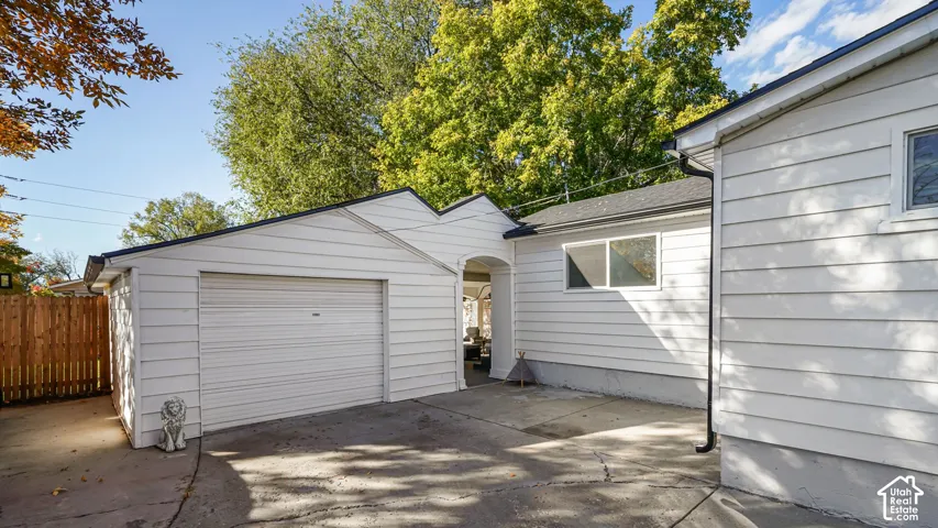 White horizontal siding exterior featuring an attached single-car garage, concrete driveway, and wooden privacy fencing