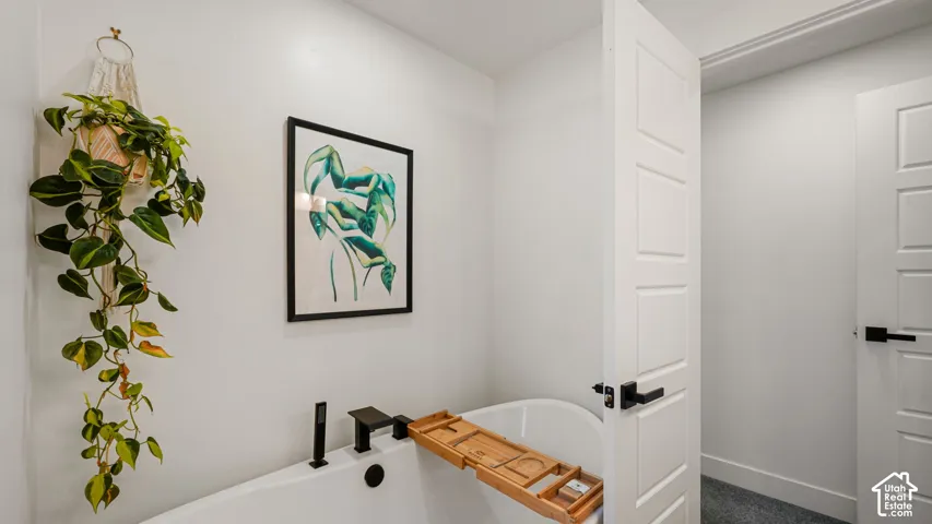 Deep soaking tub featuring a matte black deck-mounted faucet and five-panel interior doors with matte black hardware
