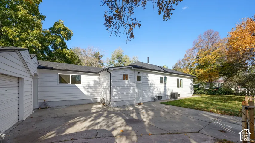 White horizontal siding exterior featuring a concrete patio, detached garage, and mature landscaping