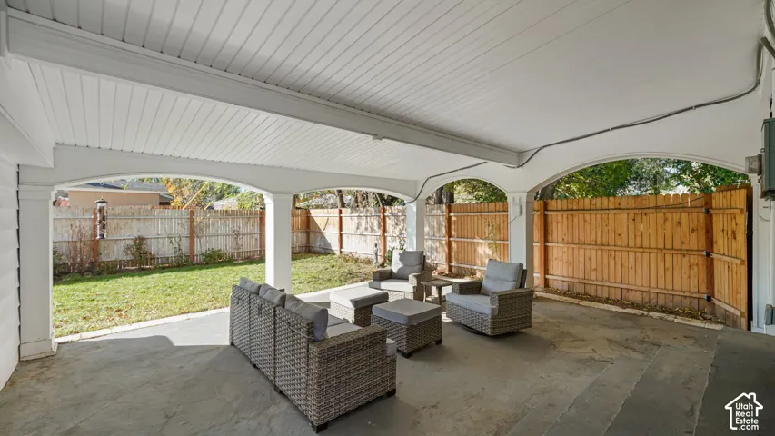Covered patio featuring architectural arched supports, a tongue-and-groove ceiling, concrete flooring, and a fully fenced backyard