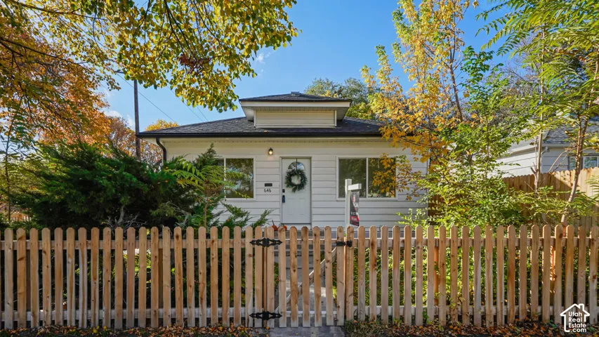 Single-story residence featuring horizontal siding, a low-pitch hip roof, and a wood picket fence enclosure