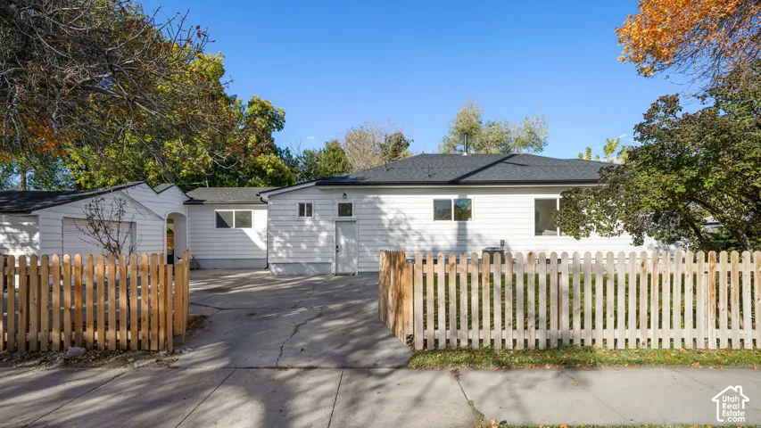 White siding exterior featuring a paved driveway, detached garage, and wood-picket fencing