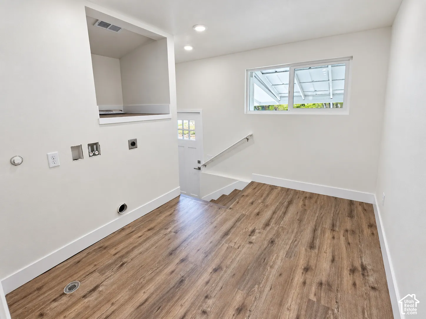 Wood-finish flooring, recessed lighting, horizontal sliding window, and built-in alcove with utility hookups