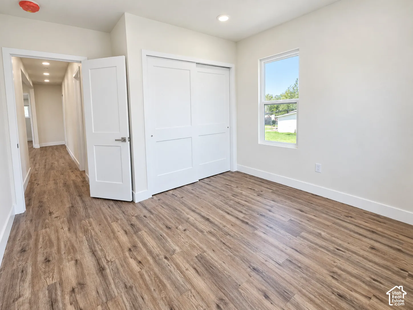 Neutral-toned room featuring wood-finish flooring, recessed lighting, and a sliding-panel closet door
