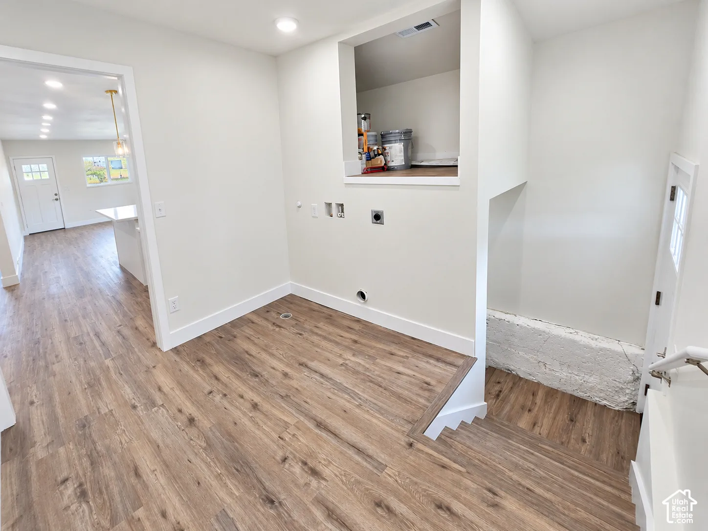 Utility area featuring wood-finish flooring, recessed lighting, integrated storage shelving, and laundry hookups