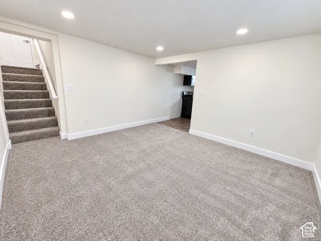 Neutral-toned carpeting, recessed ceiling lighting, staircase with carpeted treads, and wood-finish flooring in the secondary area
