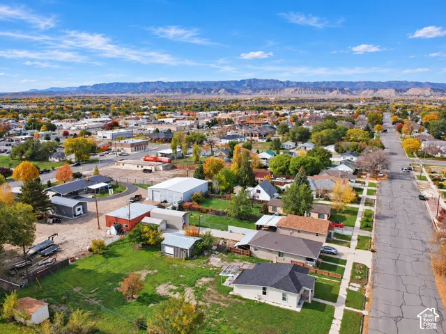 Aerial perspective of the residential property featuring a detached garage, a storage outbuilding, mature landscaping, and prominent mountain backdrops
