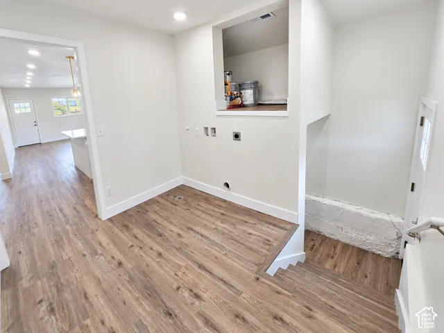 Utility area featuring wood-finish flooring, recessed lighting, integrated storage shelving, and laundry hookups