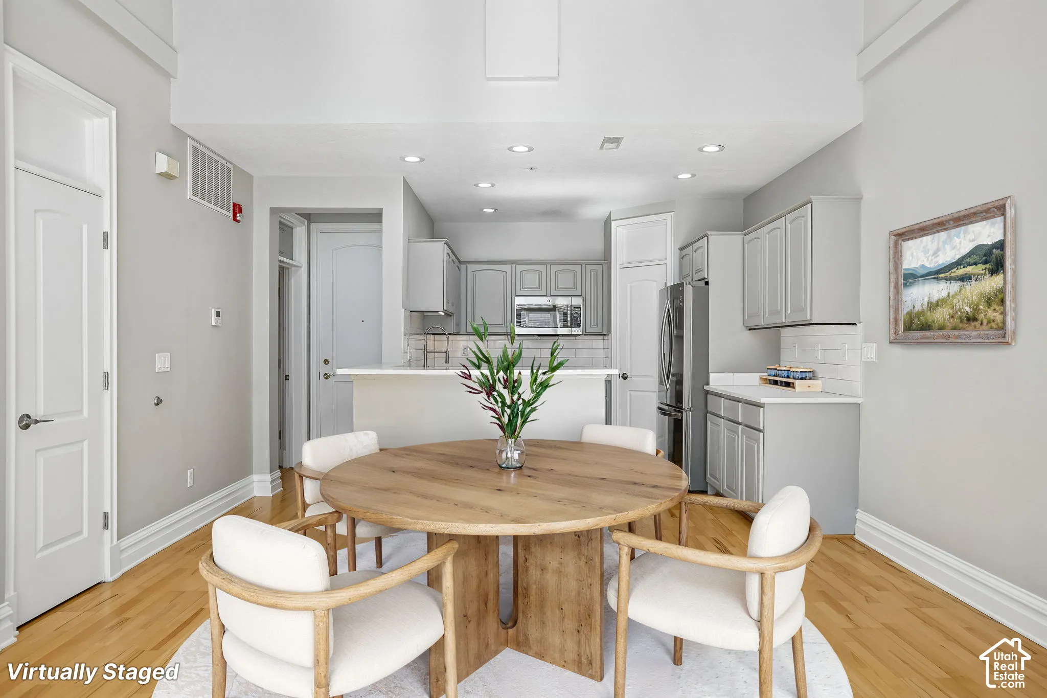 High-ceiling interior featuring recessed lighting, hardwood flooring, and a kitchen equipped with cabinetry, stainless steel appliances, and a tiled backsplash