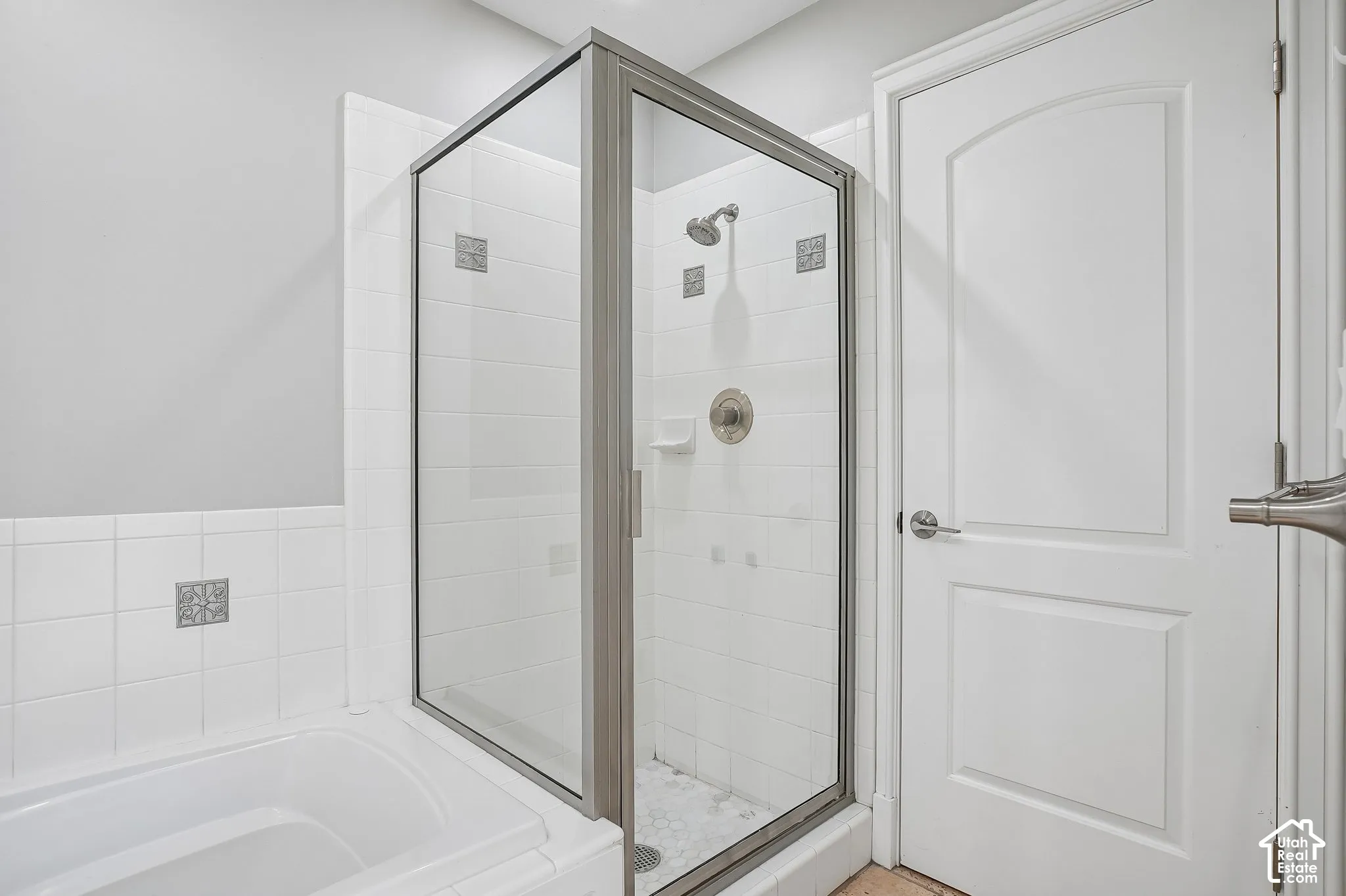Glass-enclosed shower with a brushed-nickel fixture, white subway-style wall tiling, decorative mosaic accents, and a built-in soap dish