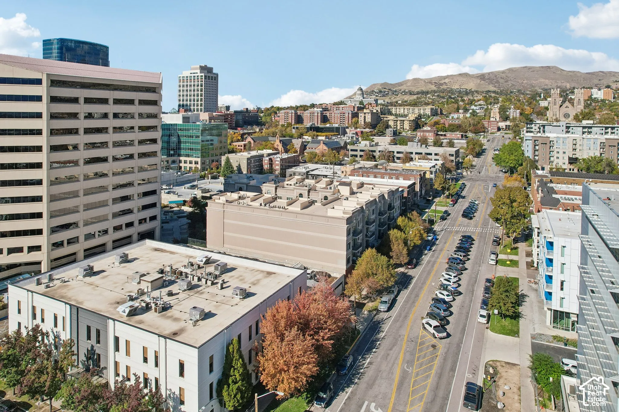 Aerial perspective featuring an urban landscape with proximity to high-rise commercial structures, local transit corridors, and mountain terrain