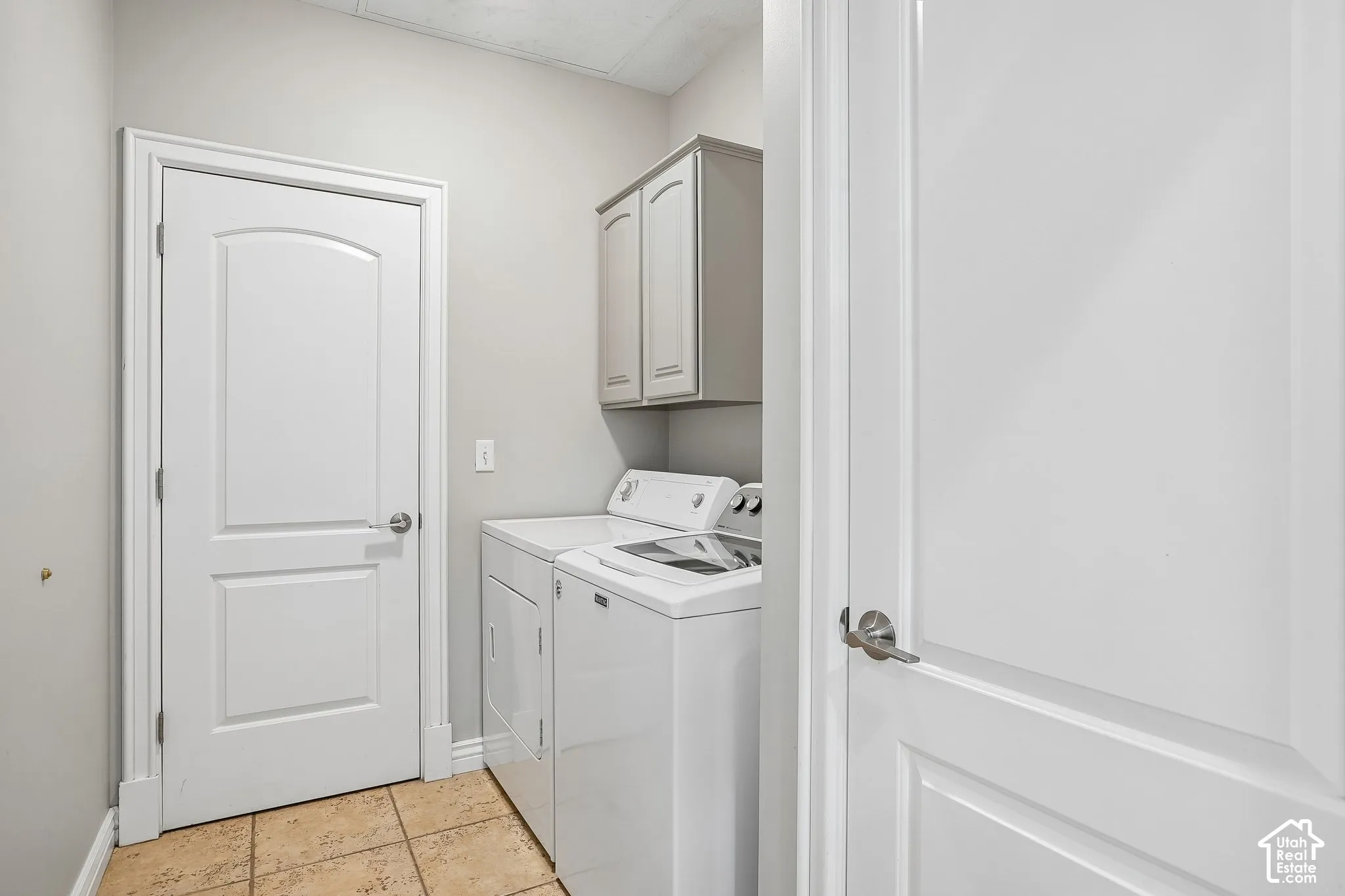 Utility room featuring neutral wall paint, tile flooring, two-panel interior doors, and wall-mounted cabinetry