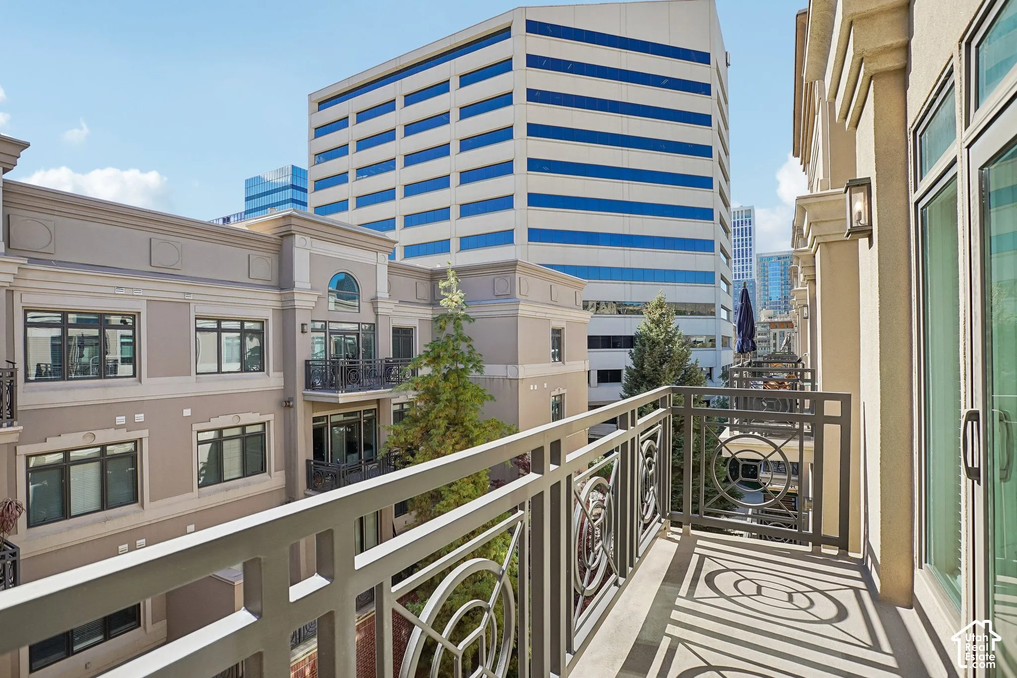 Private balcony featuring metal decorative railing, exterior wall-mounted lighting, and glass paneled door entry