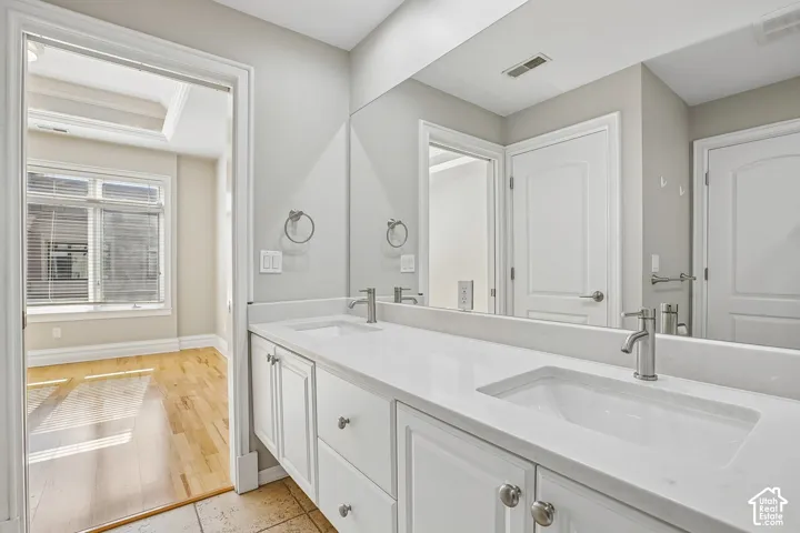 Dual-sink vanity with white cabinetry, light-toned stone-style countertop, undermount sinks, and brushed-nickel faucets, complemented by a large wall-mounted mirror