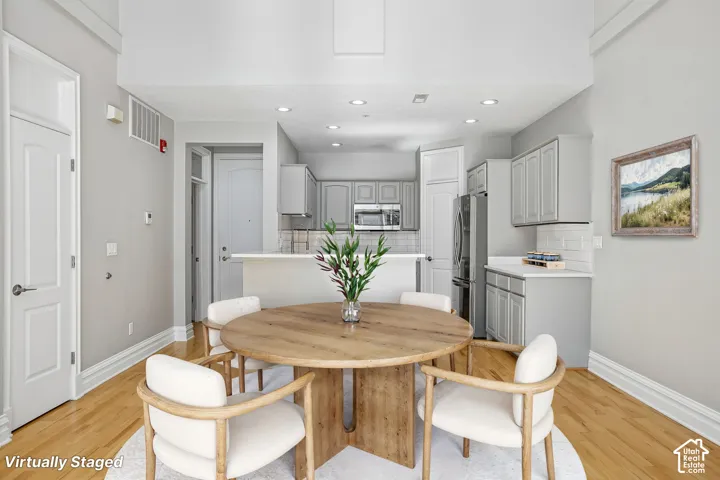 High-ceiling interior featuring recessed lighting, hardwood flooring, and a kitchen equipped with cabinetry, stainless steel appliances, and a tiled backsplash