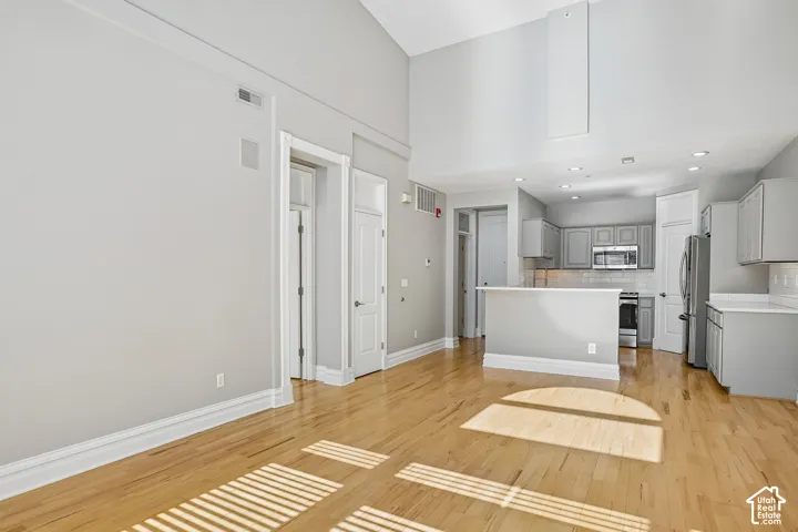 Vaulted ceilings, wood-finish flooring, kitchen peninsula, recessed lighting, and crisp neutral-tone cabinetry