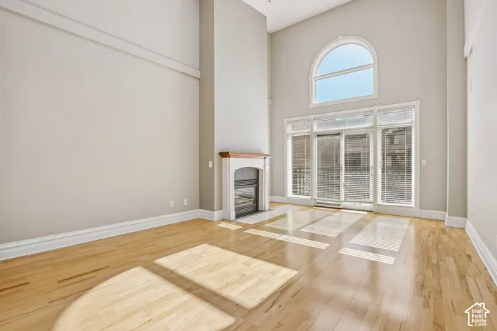 Vaulted ceilings, wood-finish flooring, fireplace with a mantel, arched window, and sliding glass door