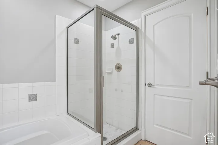 Glass-enclosed shower with a brushed-nickel fixture, white subway-style wall tiling, decorative mosaic accents, and a built-in soap dish