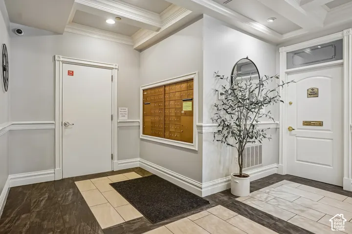 Entryway featuring coffered ceilings, multi-tonal tile flooring, wainscoting, and a built-in recessed mail station