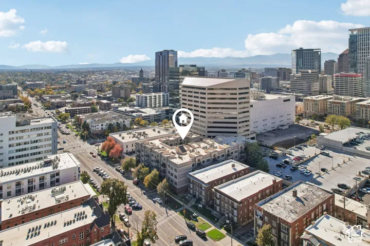 Aerial perspective of a multi-story urban complex featuring a flat roofline, neutral exterior facade, and proximity to downtown city infrastructure