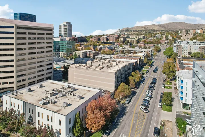 Aerial perspective featuring an urban landscape with proximity to high-rise commercial structures, local transit corridors, and mountain terrain