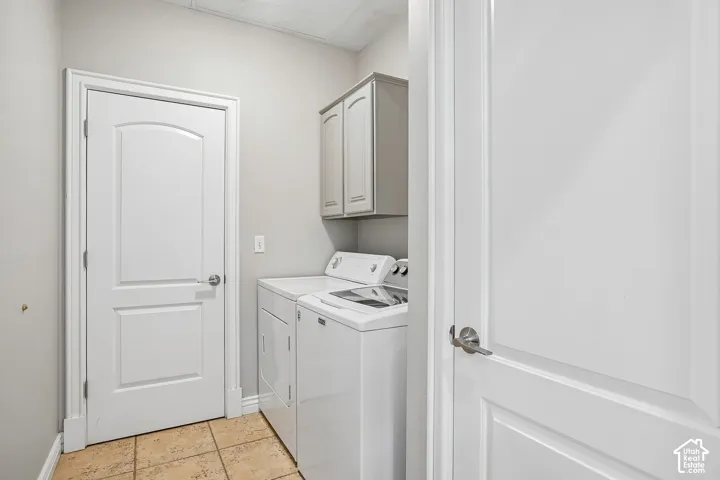 Utility room featuring neutral wall paint, tile flooring, two-panel interior doors, and wall-mounted cabinetry